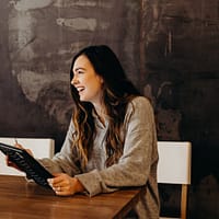 /hiring remote workers woman sitting around table holding tablet