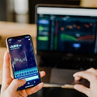 crypto trading person using phone and laptop computer