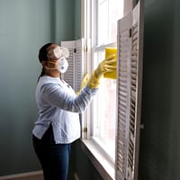 disinfection - woman in white long sleeve shirt and blue denim jeans standing beside white wooden framed glass