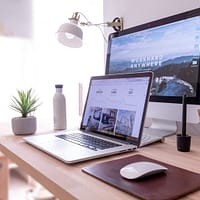 digital marketing MacBook Pro on table beside white iMac and Magic Mouse