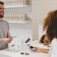 Customer Success business strategy man in grey crew-neck t-shirt smiling to woman on counter