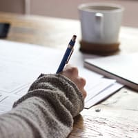 business plan person writing on brown wooden table near white ceramic mug