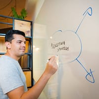 marketing strategy man in gray crew neck t-shirt standing near white wall