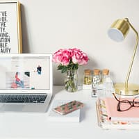 Small Business Blog MacBook Air beside gold-colored study lamp and spiral books