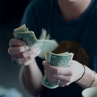 Earn Money at Home focus photography of person counting dollar banknotes