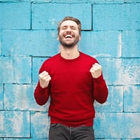 man wearing red long-sleeved shirt standing beside wall