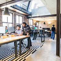 renovate your workplace man standing beside another sitting man using computer