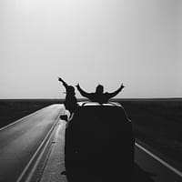 road trip grayscale photo of man riding on motorcycle on road