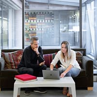 real estate agents man and woman sitting on couch using macbook