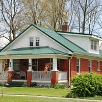 white and brown wooden house near green trees during daytime