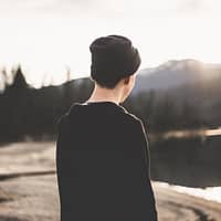 tilt shift lens photography of man standing near body of water