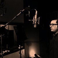 man standing in front of condenser microphone inside recording studio