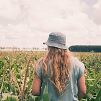 woman in grey hat standing on green grass field during daytime