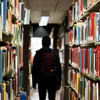 man with backpack beside a books