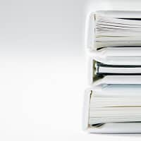 A stack of thick folders on a white surface