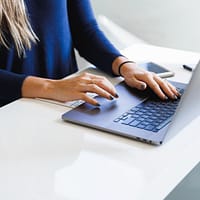 woman in blue long sleeve shirt using macbook pro