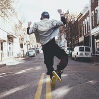 man jumping on the middle of the street during daytime