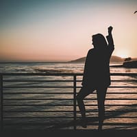 silhouette of woman standing near the fence