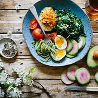 poached egg with vegetables and tomatoes on blue plate