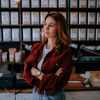 woman in brown jacket standing near black computer monitor