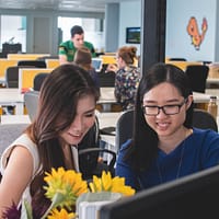 selective focus photography of two women in front of computer monitor