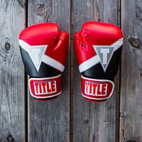 pair of red-and-black Title training gloves on grey wooden plank