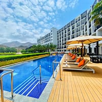 white and brown wooden lounge chairs near swimming pool during daytime