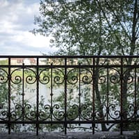 black metal fence near green trees during daytime