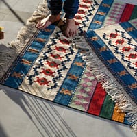 person in blue denim jeans standing on white blue and red area rug