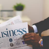 person wearing suit reading business newspaper