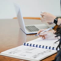 person holding pen writing on paper