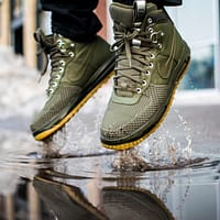 person wearing green Nike sneakers jumping on water