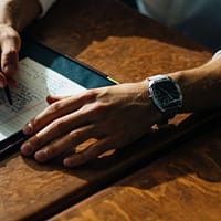 person writing on paper leaning on brown table