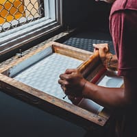 man holding printing screen near white window