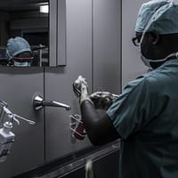 man wearing surgical suit near mirror