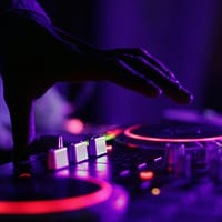 selective focus silhouette photography of man playing red-lighted DJ terminal