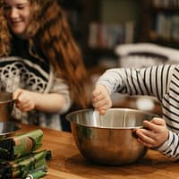 woman in black and white striped long sleeve shirt holding stainless steel bowl