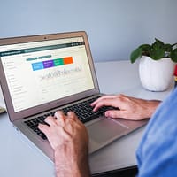 person using macbook air on white table