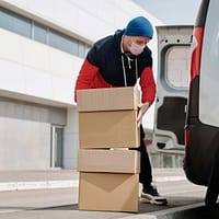 A man wearing a face mask and carrying boxes