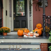 a front porch decorated for halloween with pumpkins and gourds