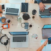 people sitting down near table with assorted laptop computers