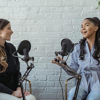 Smiling African American female guest gesticulating while having interview with journalist sitting near mic