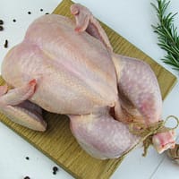 a raw chicken on a cutting board next to a slice of lemon