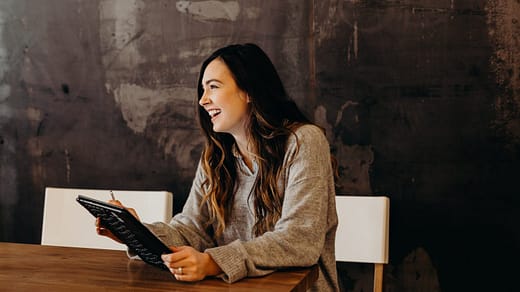 /hiring remote workers woman sitting around table holding tablet