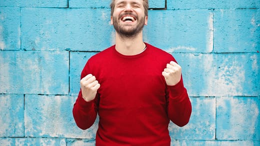 man wearing red long-sleeved shirt standing beside wall