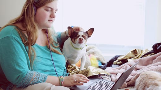 emotional marketing girl in blue jacket holding white and brown short coated puppy