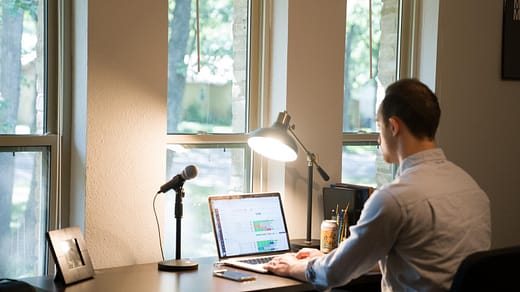 man in white dress shirt sitting on chair using laptop computer