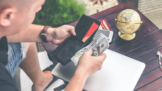 person holding wallet and US dollar bills