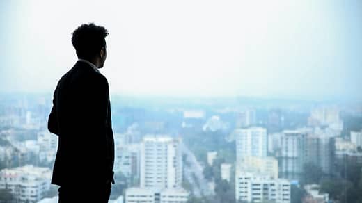 man in black suit standing on top of building looking at city buildings during daytime