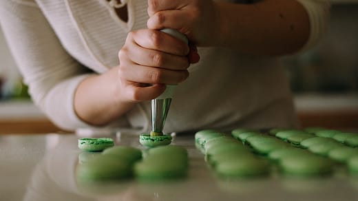 selective focus photography of woman putting icing on cupcakes